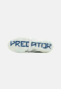 Fudbalske kopačke s bijelim gornjištem, teksturiranim dizajnom i plavim natpisom "PREDATOR" na prozirnoj potplati. Sadrže sintetički materijal.