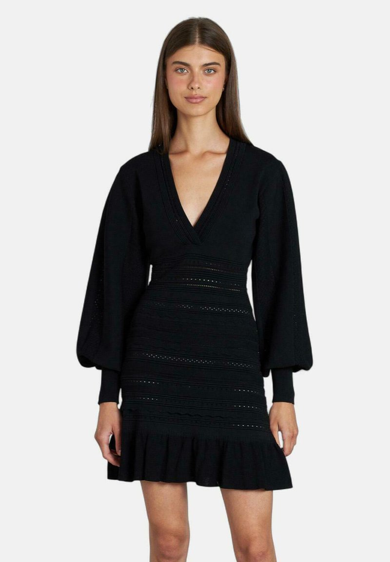 Abito knit nero con scollatura a V profonda, maniche lunghe a palloncino e orlo arricciato. Presenta dettagli testurizzati e una silhouette aderente.