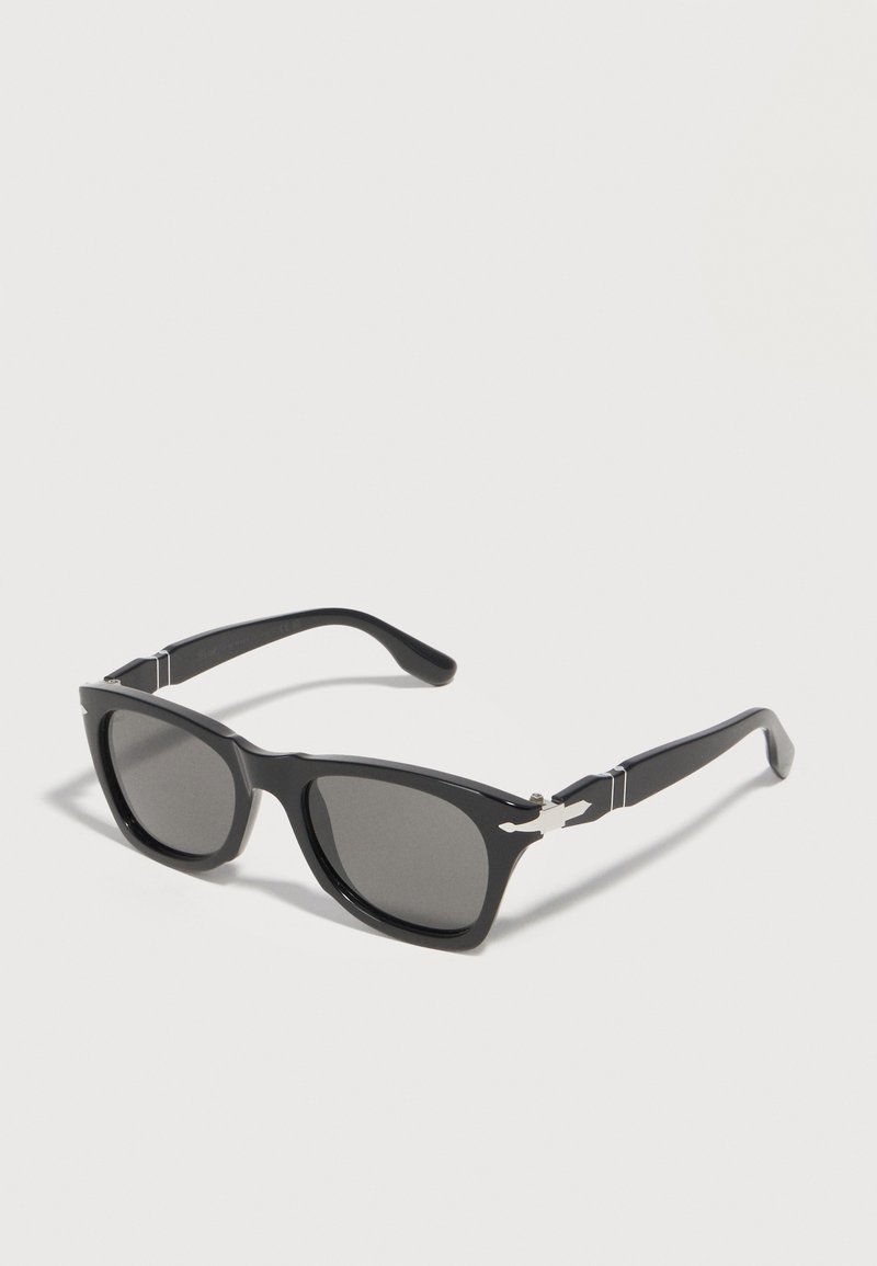 Μαύρα ορθογώνια γυαλιά ηλίου με σκούρους φακούς και ασημένιες διακοσμητικές λεπτομέρειες στους βραχίονες, εμφανιζόμενα σε λευκό φόντο.