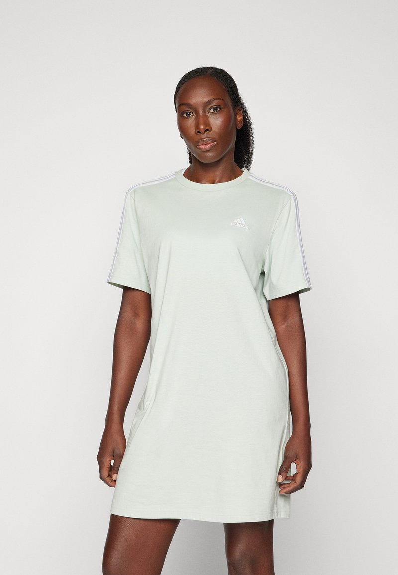 Robe en coton vert clair avec des manches courtes, un col rond et un logo Adidas blanc ; design simple avec des rayures latérales contrastantes.