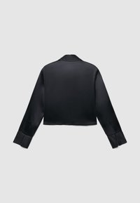 Schwarze Satin-Cropped-Jacke mit langen Ärmeln, perforierten breiten Manschetten und passendem perforiertem Kragen, von hinten auf einem einfarbigen Hintergrund gezeigt.