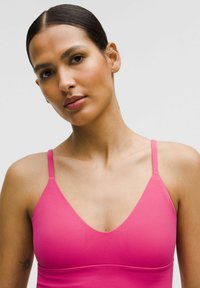 Bralet roz cu decolteu adânc în V, bretele subțiri ajustabile și o textură netedă, elastică, fără modele sau accesorii vizibile.