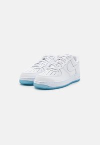 Sneakers bianchi in pelle con area della punta perforata, suola traslucida azzurro chiaro e lacci grigi. Logo laterale e colletto imbottito per il comfort.