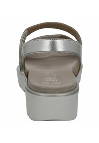 Sandali metallici argento con una fascia larga, soletta imbottita e una suola piatta chunky color beige, mostrati dalla vista posteriore.