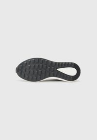 Zwarte rubberen sneakerzool met een gestructureerd grippatroon, een witte accent langs de rand en een afgeronde vorm.