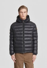 Giacca a vento nera con cappuccio, caratterizzata da sezioni trapuntate orizzontali, tasche laterali con zip e polsini elastici per una vestibilità aderente.