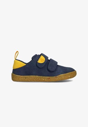Zapatilla deportiva para niño azul marino y amarilla con dos tiras de velcro y suela marrón texturizada, mostrada de perfil sobre fondo blanco.