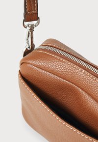 Hnědá kožená crossbody taška s texturovaným povrchem, stříbrným zipem a odnímatelným popruhem s prošíváním.