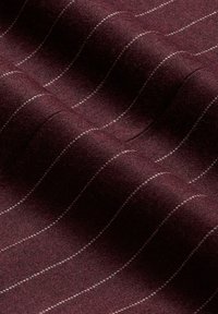 Burgundy látka s texturovaným povrchem, která má tenké, bílé vlnité pruhy. Materiál vypadá měkce a má mírný lesk.