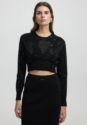 Cardigan noir court avec un design texturé, doté de manches longues, d'un col en V, d'une fermeture à boutons et d'une finition côtelée ajustée.