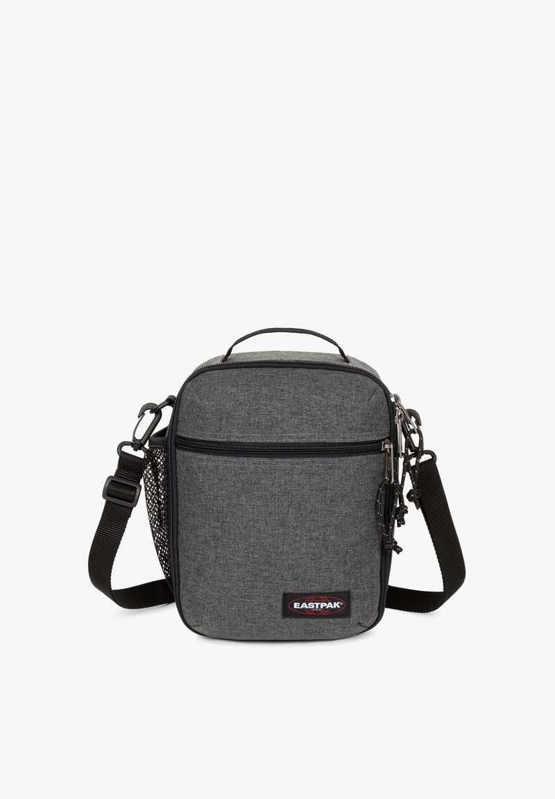 Malá šedá messenger taška vyrobená z textilu, se zipovým uzávěrem, nastavitelným popruhem, horním držadlem a bočním kapsou ze síťoviny. Obsahuje logo EASTPAK.