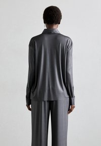 Grå satin skjorta med lång ärm och krage, med en avslappnad passform och knappade manschetter; kombinerad med matchande byxor.