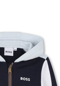 Granatowy i biały dziecięcy rozpinany hoodie z jasnoniebieskim kapturem oraz logo BOSS na klatce piersiowej i przy suwaku.