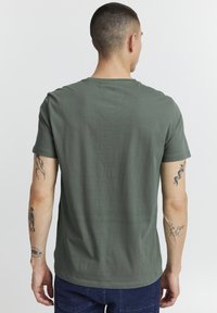 Olivenfarget bomulls-T-skjorte med rund hals og korte ermer, som har en jevn tekstur og en avslappet passform.