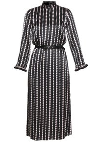 Largo vestido negro de satén, con patrones de lunares rosas verticales, cuello alto, puños con volantes y un cinturón negro en la cintura.