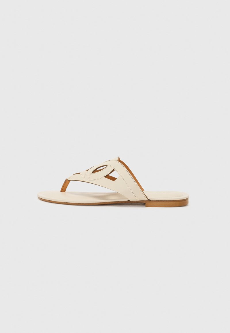 Sandale din piele cu un guler crem, având un design cu decupajuri și accente maronii. Talpă plată și construcție minimalistă.