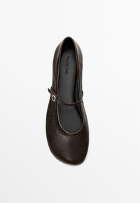 Brown leather ballet flat with a rounded toe, slim strap across the instep, and a smooth interior texture.