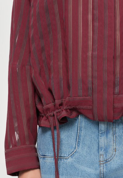 Maroon striped blouse with a drawstring hem. Made of light fabric, featuring vertical stripes in gray and beige. Long sleeves with rolled cuffs.