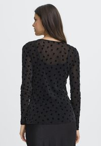 Sort lang�ærmet top med et gennemsigtigt stof og teksturerede hjerter. Slim-fit silhuet, rund halsudskæring og en glat ryg.