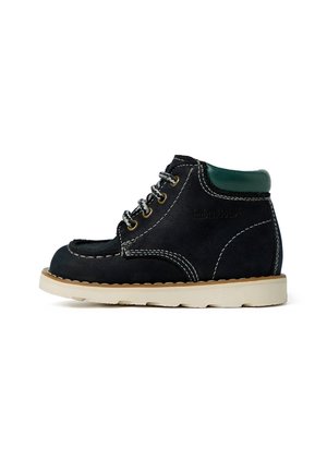 Stivale alla caviglia in suede nero con colletto verde, cuciture bianche e suola in gomma beige. Presenta occhielli metallici rotondi e una texture liscia.