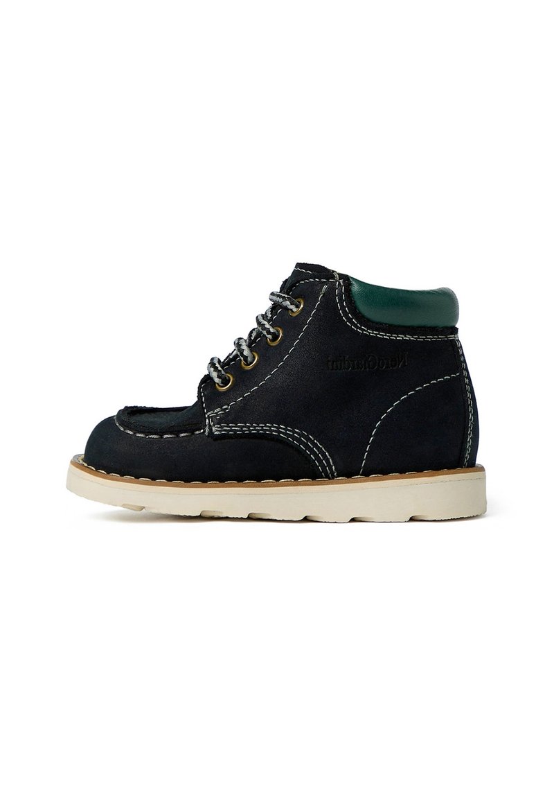 Bottines noires en suède à lacets avec un col vert, des coutures blanches et une semelle en caoutchouc beige. Présente des œillets en métal ronds et une texture lisse.