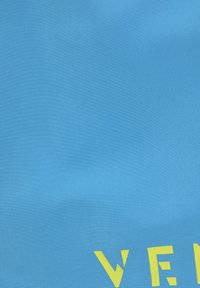 Il tessuto blu presenta grandi lettere gialle in grassetto. La texture appare liscia con una leggera lucentezza. Sottolinea un design moderno e semplice.