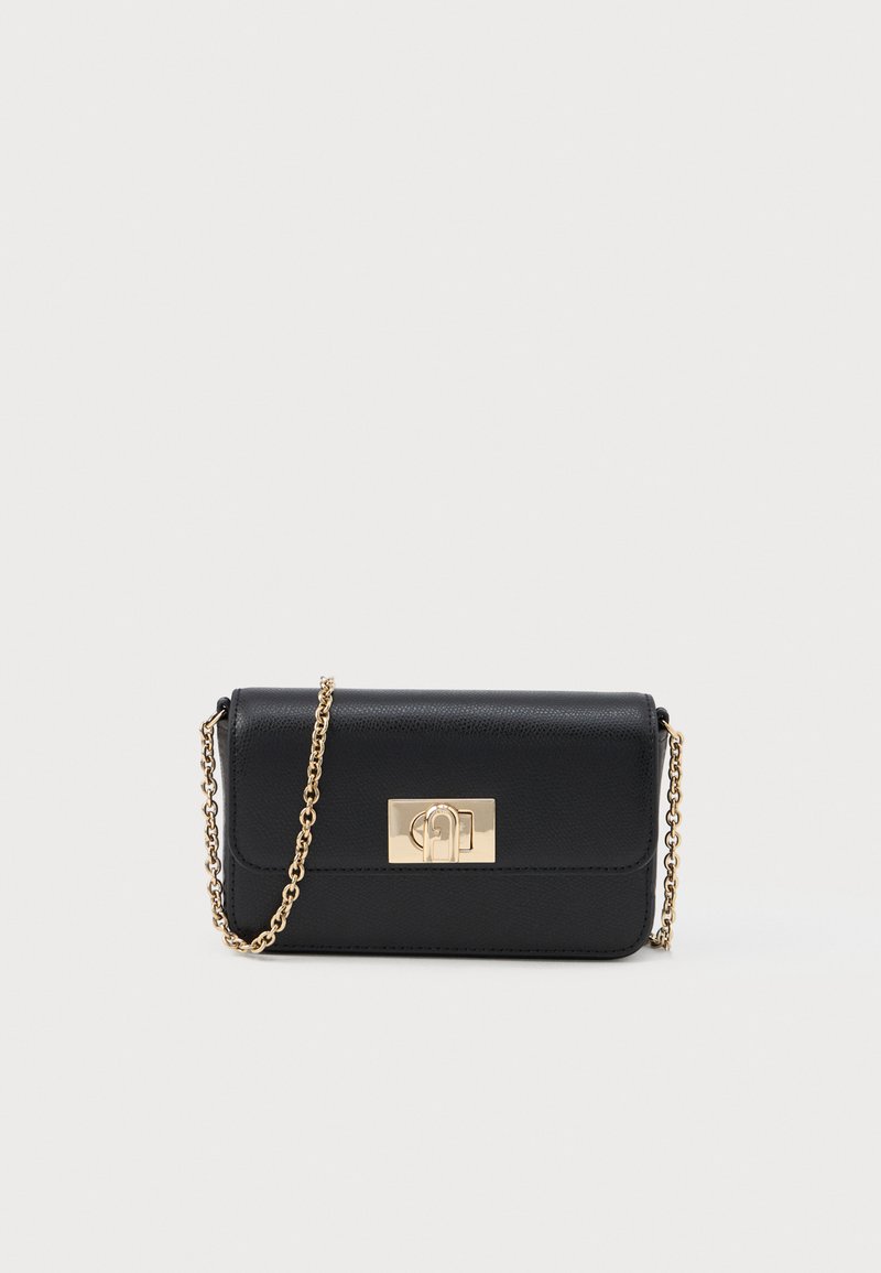 Bolso de piel negra tipo bandolera con correa de cadena dorada y cierre rectangular dorado en la parte delantera, sobre un fondo claro y liso.