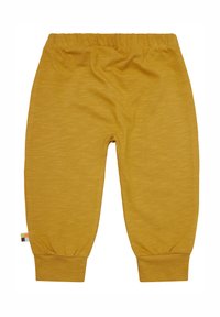 Senfgelbe Hose aus weichem, dehnbarem Material mit einem elastischen Bund und gerippten Bündchen. Mit einem kleinen, mehrfarbigen Etikett an der Seite.