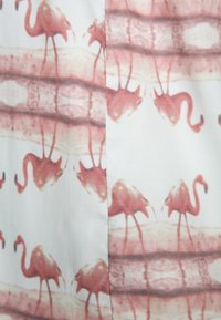 Tissu à motif flamant rose avec une texture douce ; présente des flamants roses clairs entourés de lignes ondulées dans des tons terre doux.
