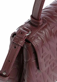Borsa a mano in pelle bordeaux con motivi geometrici in rilievo, finitura testurizzata e tracolla regolabile con dettagli in metallo.