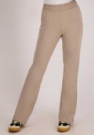 Beige katoenen sweatpants met een elastische tailleband, voorzien van een rechte pijp en een comfortabele pasvorm, gecombineerd met zwart-gele sneakers.