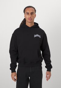 Black hooded sweatshirt with ribbed cuffs and hem, featuring a front pocket and white printed text design on the chest.