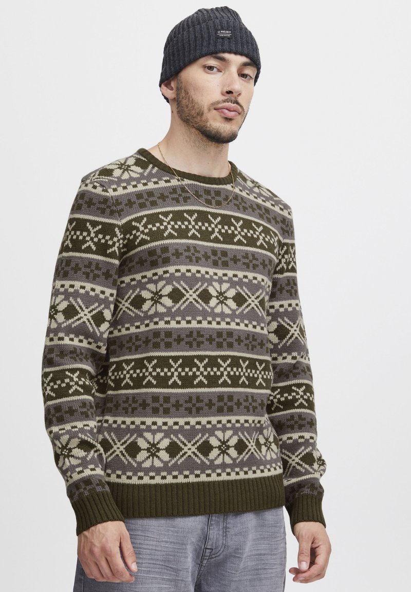 Grüner, gemusterter Strickpullover mit Schneeflocken- und Quadratmuster in Beige und Grau, mit gerippten Bündchen, Rundhalsausschnitt und weicher Textur.