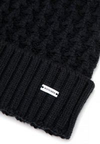 Černá pletená čepice s texturovaným vzorem a žebrovaným lemem. Má stříbrný štítek s logem "WITTCHEN" na boku. Vyrobena z měkké vlněné směsi.