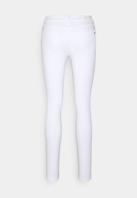 Jeans skinnies blancos con una textura suave y elástica. Cuentan con una cintura de altura media, pasadores para cinturón y dos bolsillos traseros. Diseño minimalista.