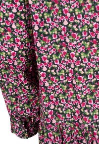 Robe fleurie avec un fond noir et des fleurs roses et vertes, en tissu doux, avec un ourlet en dégradé et des poignets froncés.
