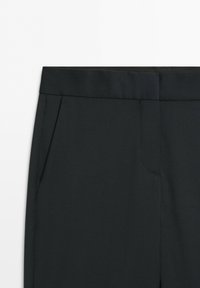 Black tailored pants with a waistband and side pockets visible on a light background.