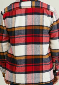 Rutet fleecejakke i rød, hvid, marineblå og sennepsfarve; afslappet pasform med en knaplukning klaplomme på ærmet.