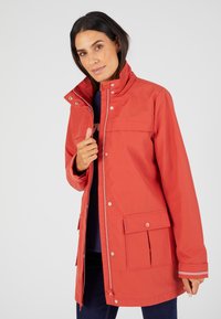 Veste imperméable rouge avec un col haut, des boutons-pression, des poches avant et des accents rayés sur les manches. Matériau lisse et durable.
