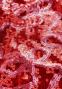 Punainen paljettil fabric, jossa on toisiinsa kietoutuvia vaaleanpunaisia ja punaisia pyöreitä paljetteja, luoden tekstuurin ja heijastavan pinnan, jolla on aaltoileva kuvio.
