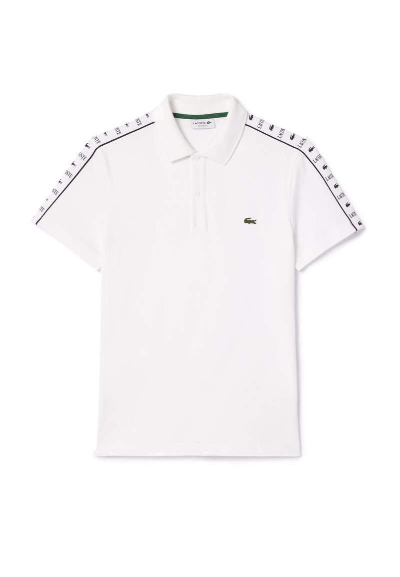 Polo shirt blanc en coton, avec un logo brodé vert, un col à deux boutons, et des accents noirs avec le nom de la marque répété sur les manches.