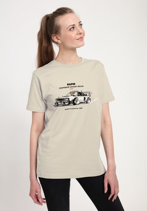 Lichtbeige t-shirt met een grafisch ontwerp van een raceauto en de tekst "RAPID ARTEKIST TRACK STAR," met een ontspannen pasvorm en een ronde halslijn.