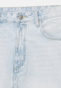 Svetlomodré rifľové nohavice detailne zobrazujú pás, gombík, prednú kapsu a detaily šitia.