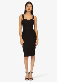 Schwarzes, tailliertes Kleid mit strukturiertem Oberteil, breiten Trägern und goldenen Akzenten. Mittellang mit einer glatten Textur, die die Silhouette betont.