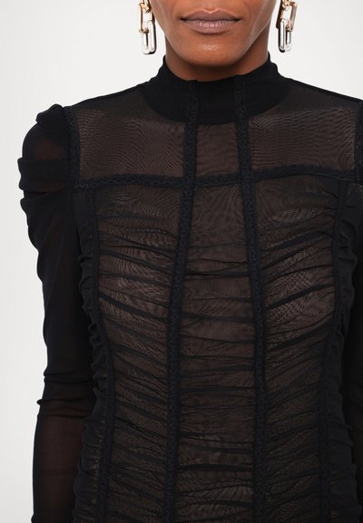 Bluză neagră cu guler înalt și material transparent texturat. Prezentă pliseuri orizontale și dantelă delicată pe cusături.