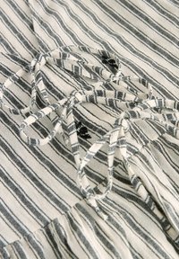 Tissu rayé en blanc et noir, doté d'un détail de nœud. La texture semble tissée avec des lignes verticales et horizontales.