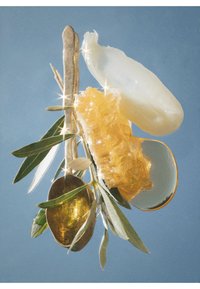 Gullfarget skje, gjennomsiktig stykke og honningkake suspendert med grønne blader på blå bakgrunn; skinnende og teksturerte elementer.