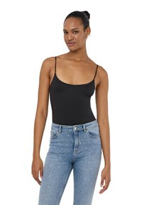 Body nero senza maniche con spalline sottili, abbinato a jeans azzurri chiari con borchie argentate sparse. Tessuto liscio con un design aderente.