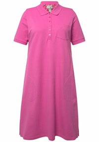 Abito polo rosa con maniche corte, patta dei bottoni e tasche laterali. Il materiale è morbido e ha una texture liscia; presenta un accento floreale all'interno del colletto.