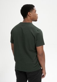 Donkergroen katoenen T-shirt met korte mouwen en een ronde hals. Glad textuur, aansluitend ontwerp. Geen zichtbare patronen of accenten.